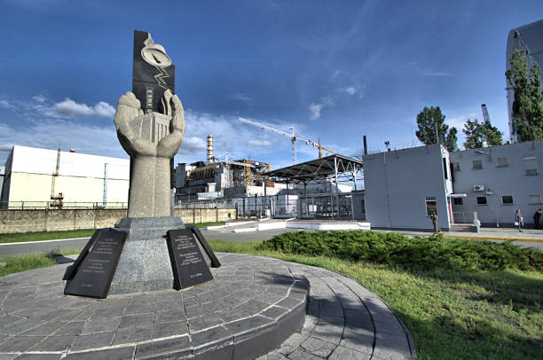Chernobyl, Ukraine - 16th May, 2016 : Chernobyl Monument sitting in front of the Chernobyl Power Plant. on the 14 th November 2016  the New Safe Confinement (NSC or New Shelter) arch was slipped over the existing sarcophagus over the course of five days, to help contain the radiation that is still active within the power plant.