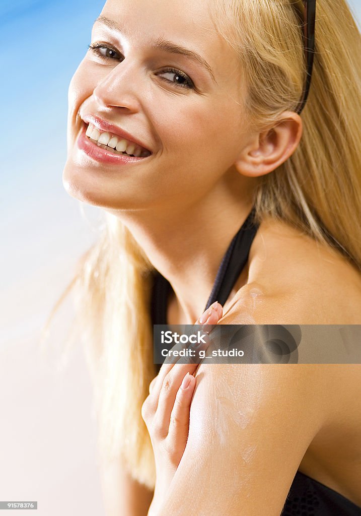Jovem bela mulher sorridente com creme protector solar na praia - Royalty-free Adulto Foto de stock