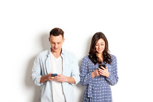istock Young couple checking mobile phone, reading a message. Technology & relationship concept. Modern romance troubles. Male & female online dating app. Touch screen, chatting, swiping, browsing, surfing. 915784210