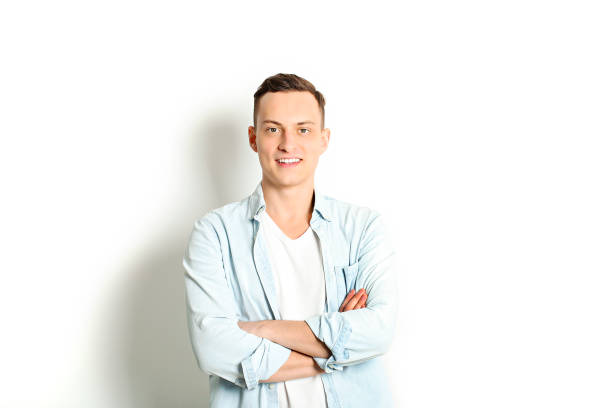 istock Handsome young man model standing, posing on white wall background, wide smile. Hipster casual street style, plain unbuttoned baby blue shirt. 915786208