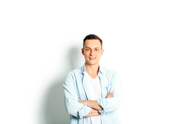 istock Handsome young man model standing, posing on white wall background, wide smile. Hipster casual street style, plain unbuttoned baby blue shirt. 915786330