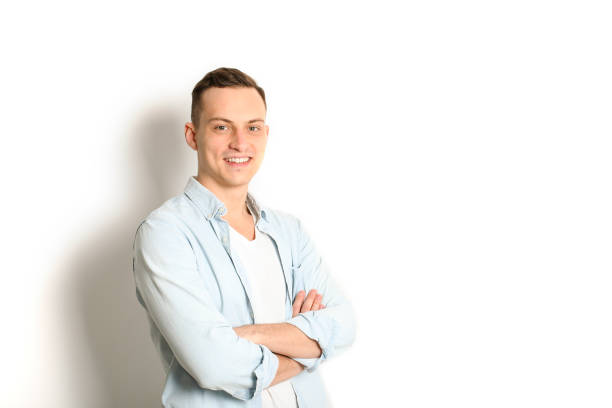 istock Handsome young man model standing, posing on white wall background, wide smile. Hipster casual street style, plain unbuttoned baby blue shirt. 915786364