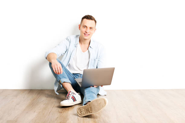 istock Handsome young man model sitting, posing on white wall background, wide smile. Hipster casual street style, plain unbuttoned baby blue shirt. 915786604