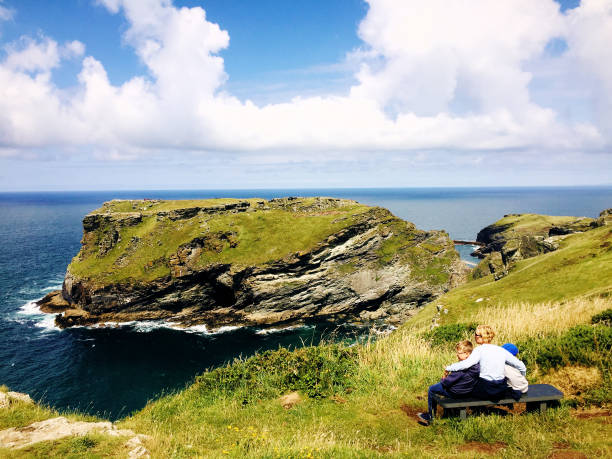 A mother sits with her boys looking at the beautiful view, Cornwall, England