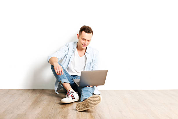 istock Handsome young man model sitting, posing on white wall background, wide smile. Hipster casual street style, plain unbuttoned baby blue shirt. 915786856