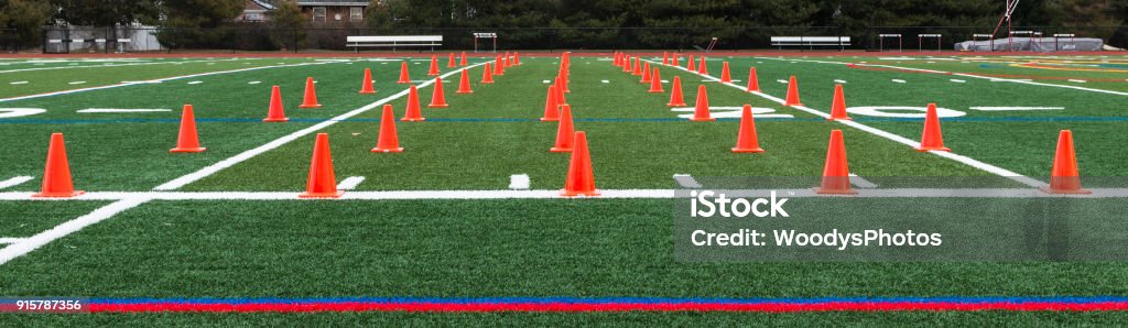 Turf field with orange cones set up for speed training Orange cones are set up on a green turf field for a track and field teams speed and agility training. Lacrosse Stock Photo