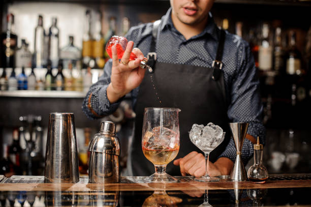 Bartender pours syrup in cocktail glass with ice