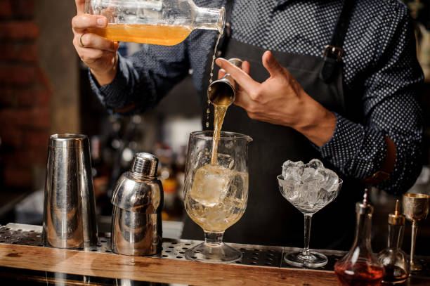 istock Bartender mixing whiskey, syrup and ice in cocktail glass 915795316