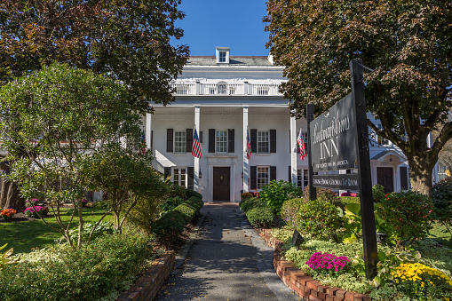 Beekman Arms Inn in Rhinebeck Village Historic District in Rhinebeck, Hudson Valley, New York. Footpath, American flags, flowers and clear blue sky are in the image. Canon EOS 6D (full frame sensor). Polarizing filter.