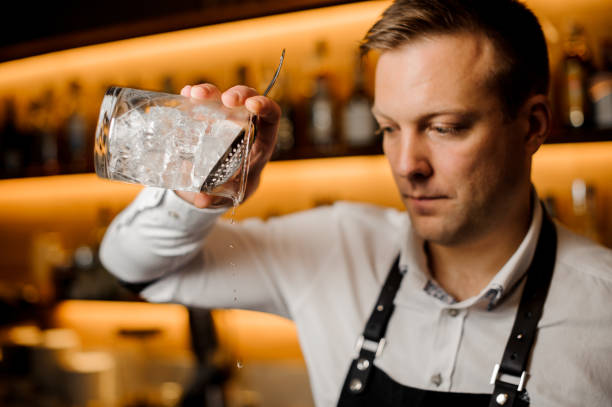 istock Barman mixing alcoholic cocktail with ice using strainer and glass 915797752