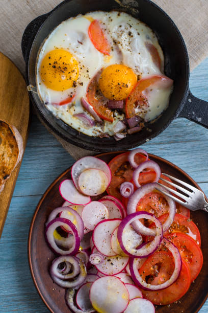 istock Fried eggs with tomatoes and spring salad with radishes and onions - rustic lunch 915799104