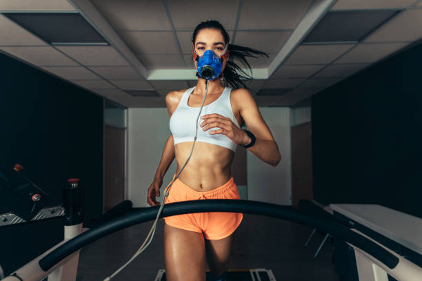 Sportswoman with mask running on treadmill Sportswoman with mask running on treadmill. Female athlete in sports science lab measuring her performance and oxygen consumption. biomechanics photos stock pictures, royalty-free photos & images