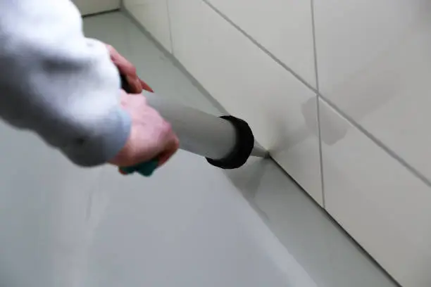 Man sealing a bath or basin with silicone