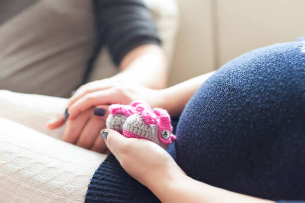 Happy future pregnant lady hands holding knitted newborn baby booties Young happy pregnant lady hands holding woollen knitted newborn baby booties. Indoors horizontal colored close-up image with soft vintage filter. cute pregnant woman with gift stock pictures, royalty-free photos & images