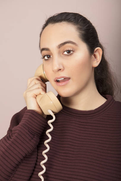 Young woman talking on a land line telephone stock photo