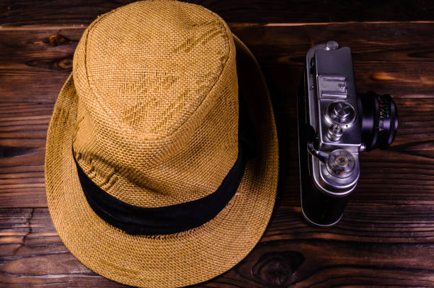istock Old rangefinder camera and hat on a wooden table. Top view 915840046