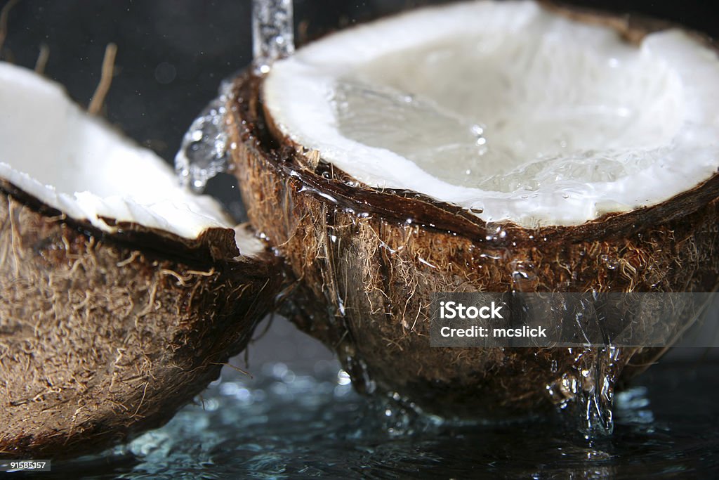 Close up of water dripping on split coconut two parts of coco in the water Coconut Stock Photo