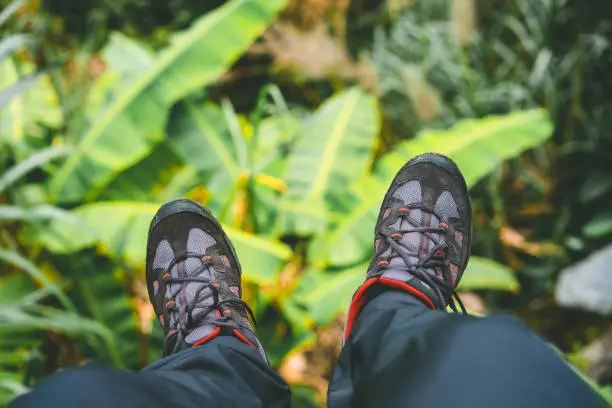 Photo of Hanging feet with trakking footwear after long hike from the mountains on Santo Antao Island, Cape Verde. Banana leaves underneath.