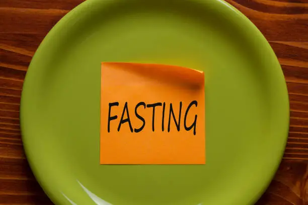 FASTING written in orange sticky note on the green plate.Business concept.Top view.