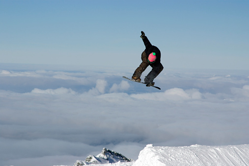 Snowboarder floats a huge backside melon grab above the clouds on Austria's Kitzsteinhorn glacier.