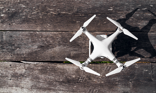 Top view of white drone standing on a wooden table.