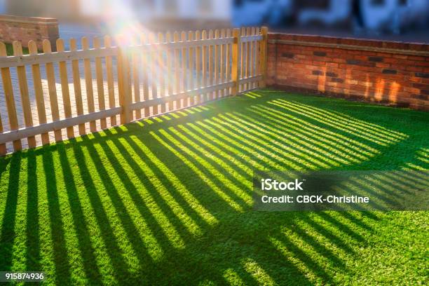 人工草の芝生の上に木製ピケット フェンスを通して輝く太陽 - 人工的のストックフォトや画像を多数ご用意 - 人工的, 芝草, 庭