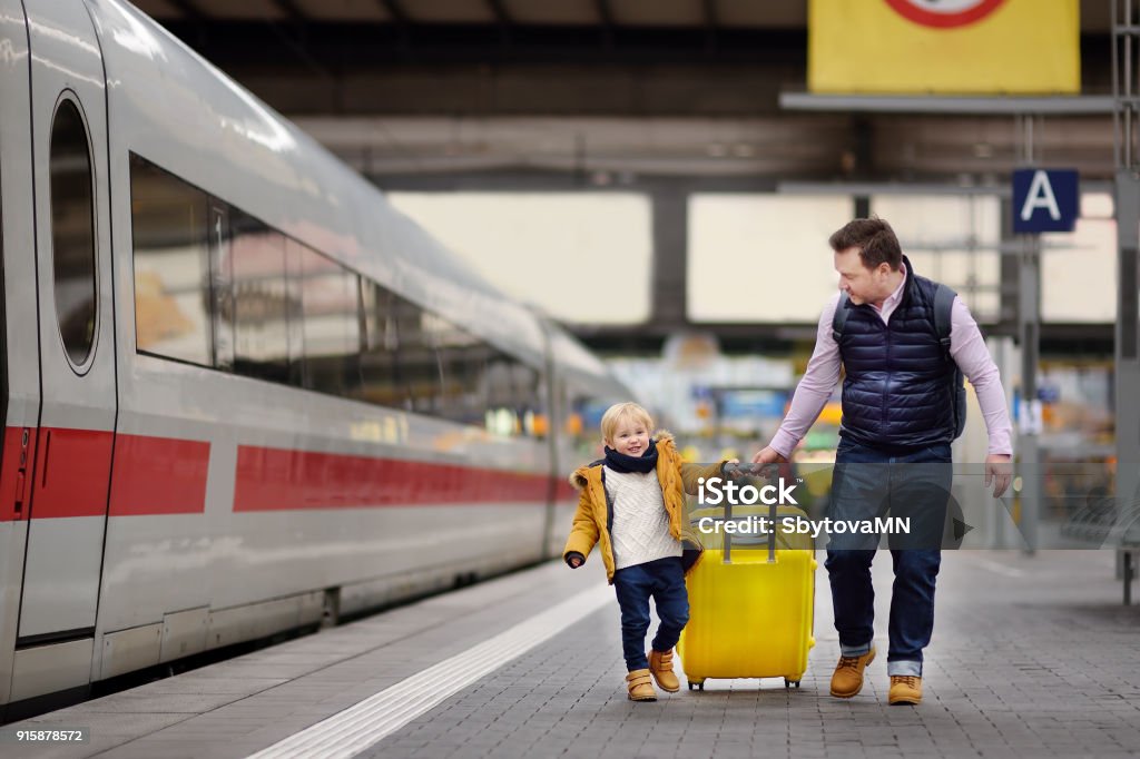 Sourire de petit garçon et son père attend un train express sur le quai de la gare ferroviaire - Photo de Famille libre de droits