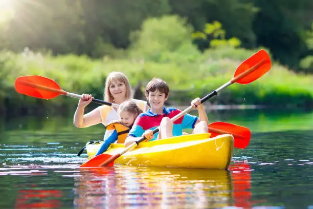 Child with paddle on kayak. Summer camp for kids. Kayaking and canoeing with family. Children on canoe. Little boy on kayak ride. Wild nature and water fun on summer vacation. Camping and fishing.