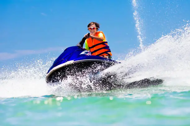 Photo of Teenager on jet ski. Teen age boy water skiing.