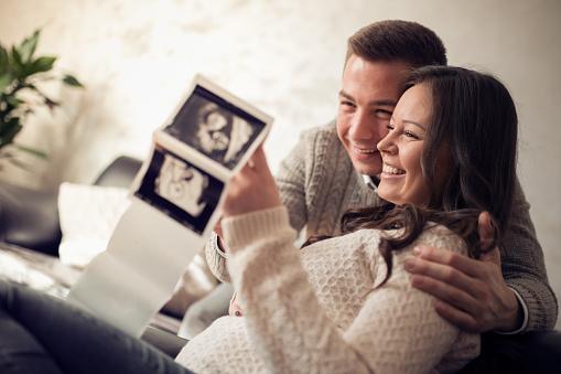 Young pregnant couple looking at ultrasound image.People,love and happiness.