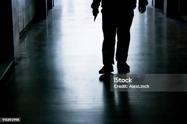 Siilhouette Of A Man Holding Sharp Object In Hand While Approaching Stock Photo - Download Image Now