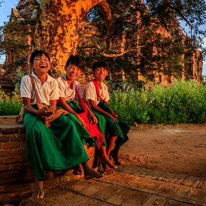 Young Burmese schoolboys with thanaka sitting next to  the ancient temple of Bagan, Myanmar (Burma)