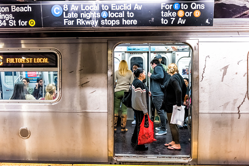 New York City: People in underground platform transit in NYC Subway Station on commute with train, people crammed crowd with open closing doors