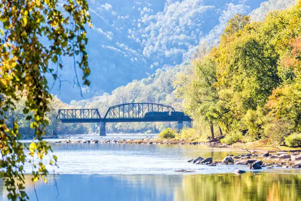 New River Gorge wide canyon water river lake during autumn golden orange foliage in fall by Grandview with peaceful calm tranquil day, closeup of bridge, train