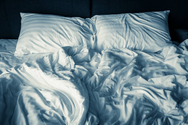 istock unmade rumpled bed with white messy pillows  in bedroom interior morning light 915911834