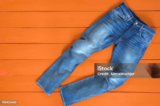 Blue Mens Jeans Denim Pants On Orange Background Contrast Saturated Color Fashion Clothing Concept View From Above Stock Photo - Download Image Now