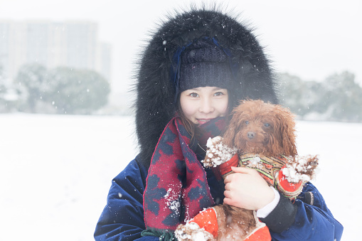 portrait of cheerful woman hugging her pet on snow,China.