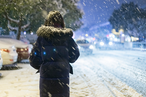 rear view of woman walking on street at night in snow,China.