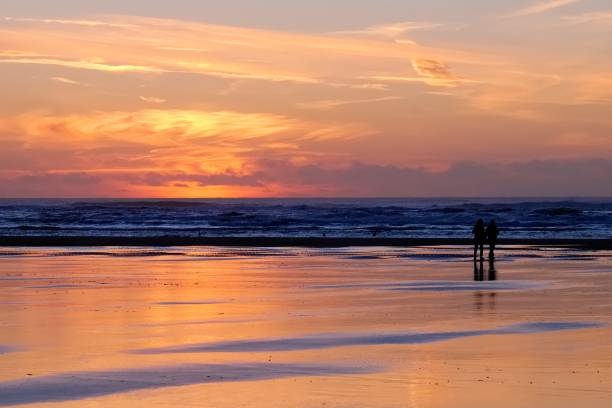 red sunset at long beach with silhouetted beachgoers - black blue escape multi colored imagens e fotografias de stock