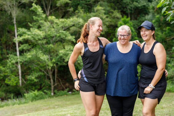 istock Mature Age Female Friends Celebrating With Personal Trainer After Completing Fun Run 915937224