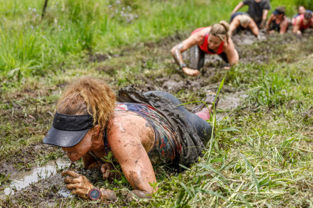 istock Woman Crawling Through Mud While Participating in Fitness Mud Run 915937566