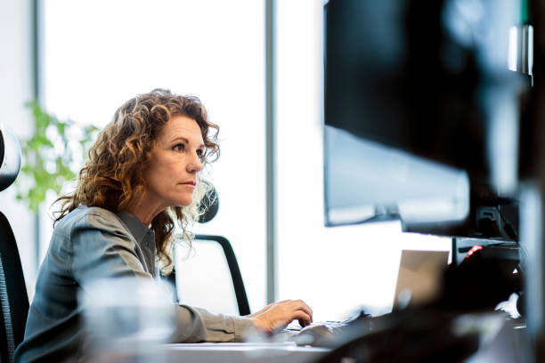 donna d'affari seria che usa il computer alla scrivania - businesswoman using computer computer monitor women foto e immagini stock