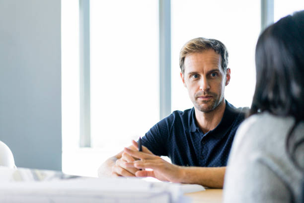 Business colleagues discussing at table in office Business colleagues discussing at table. Coworkers is sitting at office. They are in smart casuals. serious talk stock pictures, royalty-free photos & images