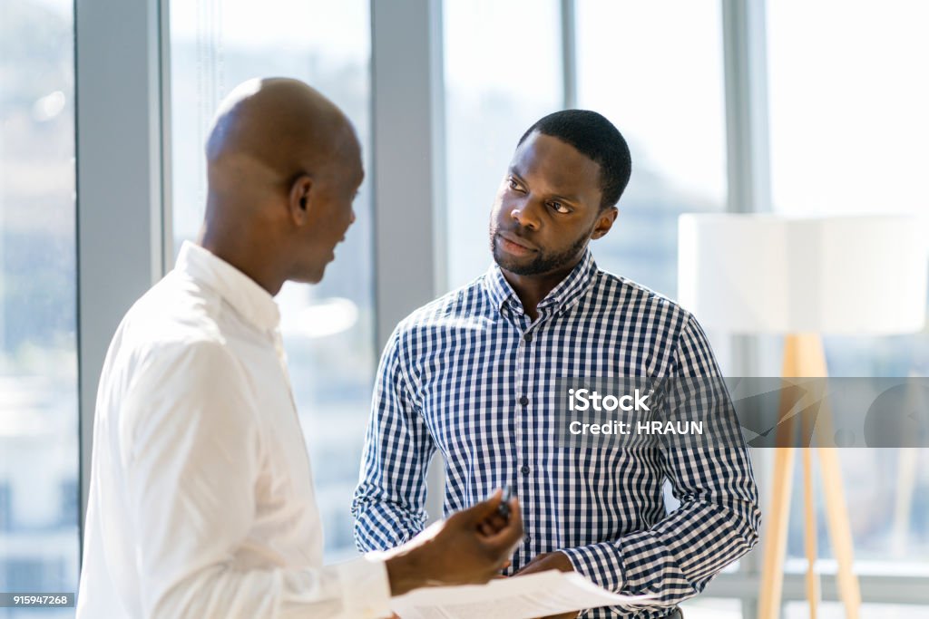 Colleghi maschi discutono su documento in ufficio - Foto stock royalty-free di Scambio d'idee