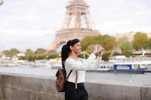 Photo of Young woman standing on embankment in Paris and watching photos