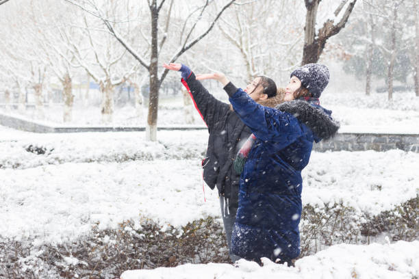 two cheerful women looking up and feeling snow,China.