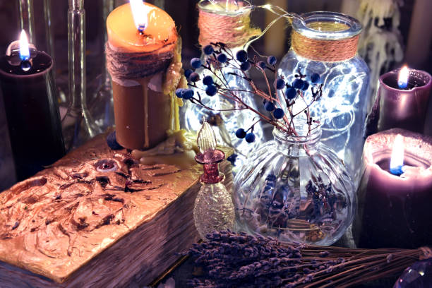 istock Old black magic book with octopus on cover, black candles and bottles 915969614