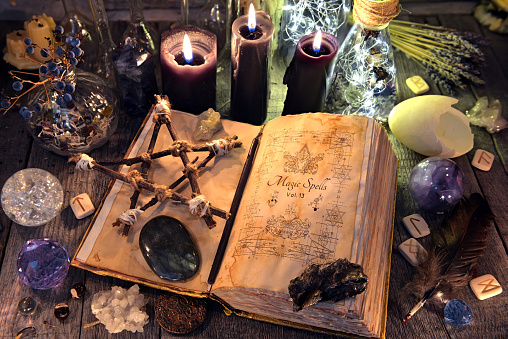 Old witch book with pentagram, black candles, crystals and ritual objects