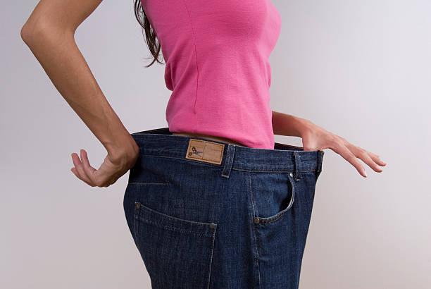 Woman wearing large jeans stock photo