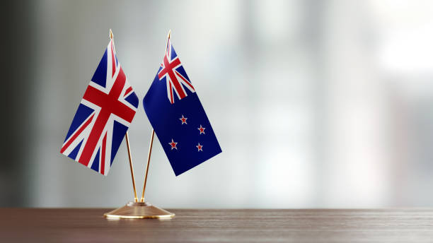 nouvelle-zélande et paire de drapeau britannique sur un bureau sur fond défocalisé - new zealand flag photos photos et images de collection